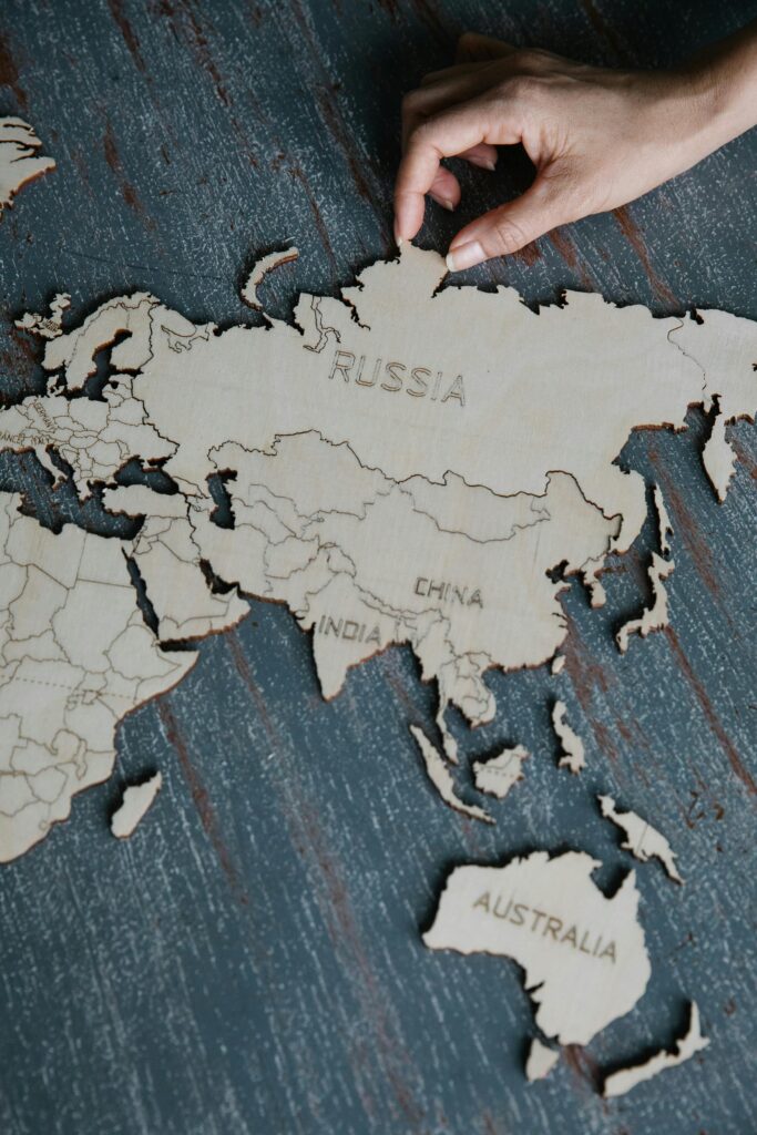 Close-up of a hand interacting with a wooden world map on a rustic surface.